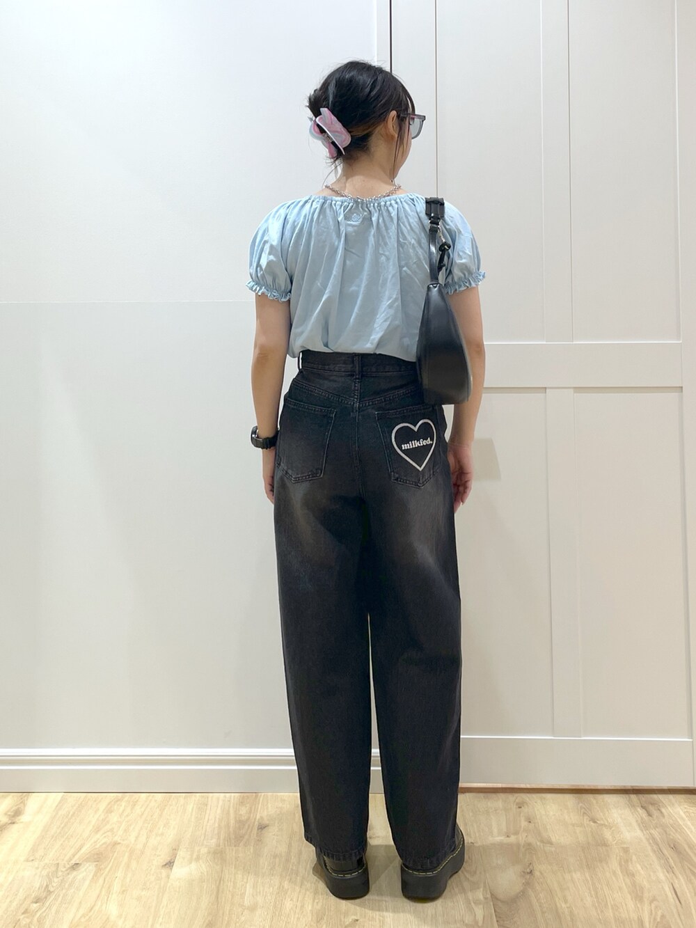ブラック系のデニムパンツ、ブラック系のブーツ、ブラック系のハンドバッグを着用したレディースの春コーディネートの2枚目の写真