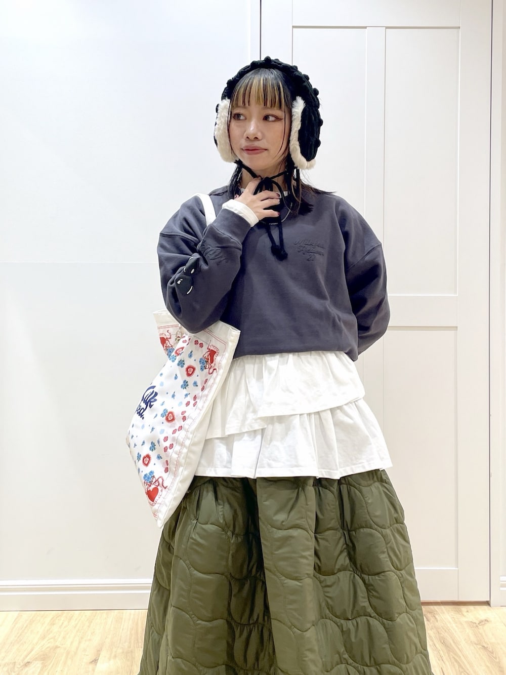 グリーン系のスカート、ホワイト系のTシャツ/カットソー、ホワイト系のトートバッグを着用したレディースの秋コーディネートの4枚目の写真