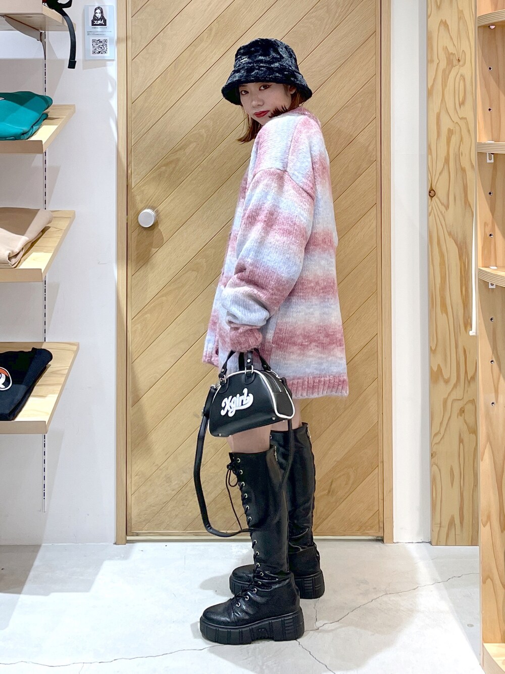 ブラック系のショルダーバッグ、ブラック系のブーツ、レッド系のカーディガン/ボレロを着用したレディースの秋コーディネートの3枚目の写真