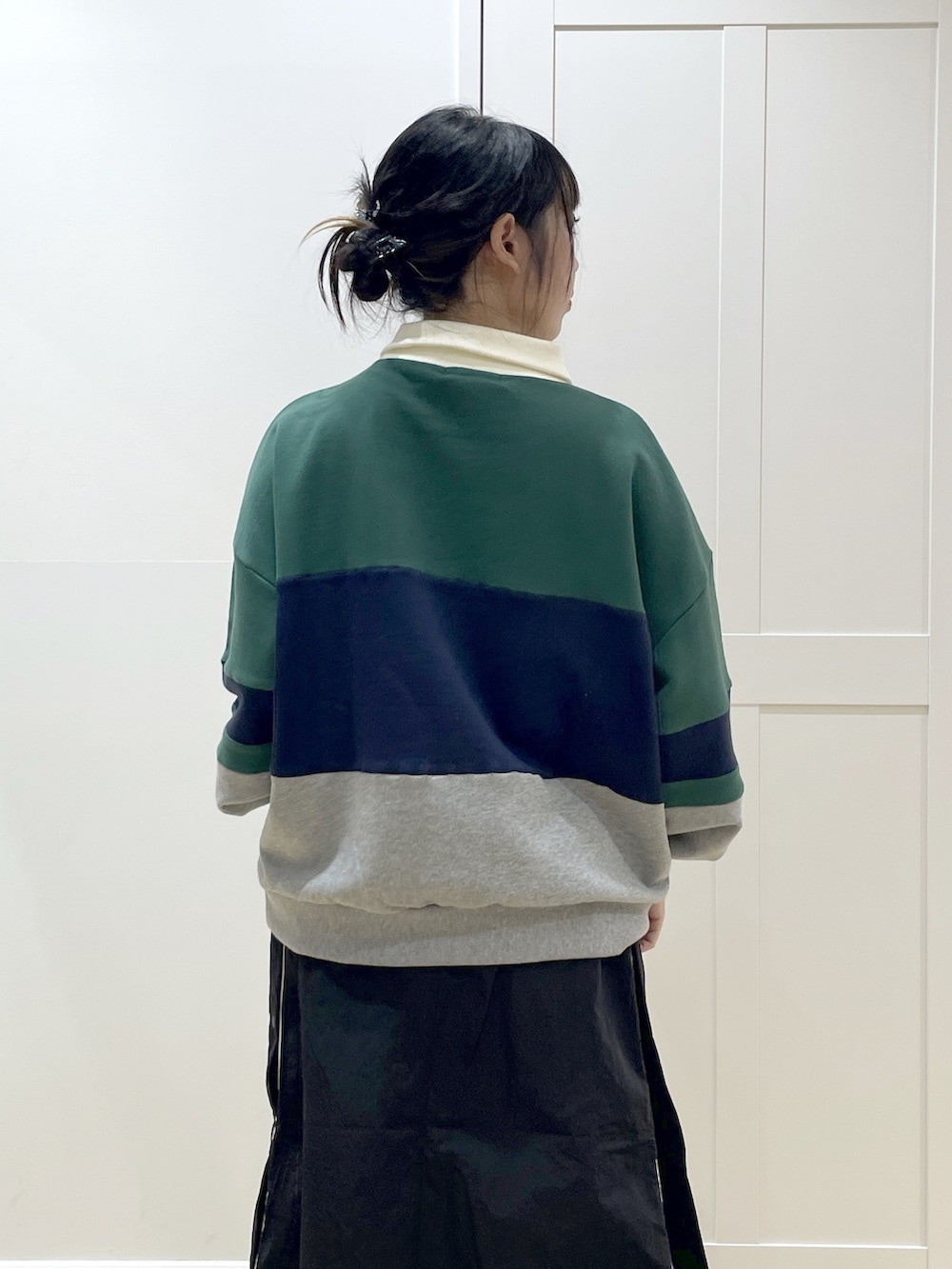 グリーン系のスウェット、ブラック系のスカート、ブルー系のトートバッグを着用したレディースの冬コーディネートの8枚目の写真