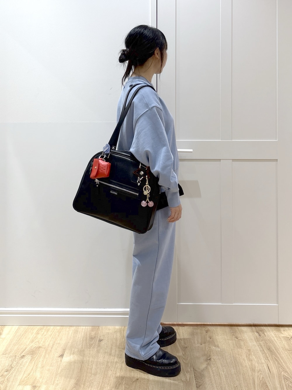 ブラック系のブーツ、ブルー系のスウェットパンツ、グリーン系のボストンバッグを着用したレディースの春コーディネートの3枚目の写真