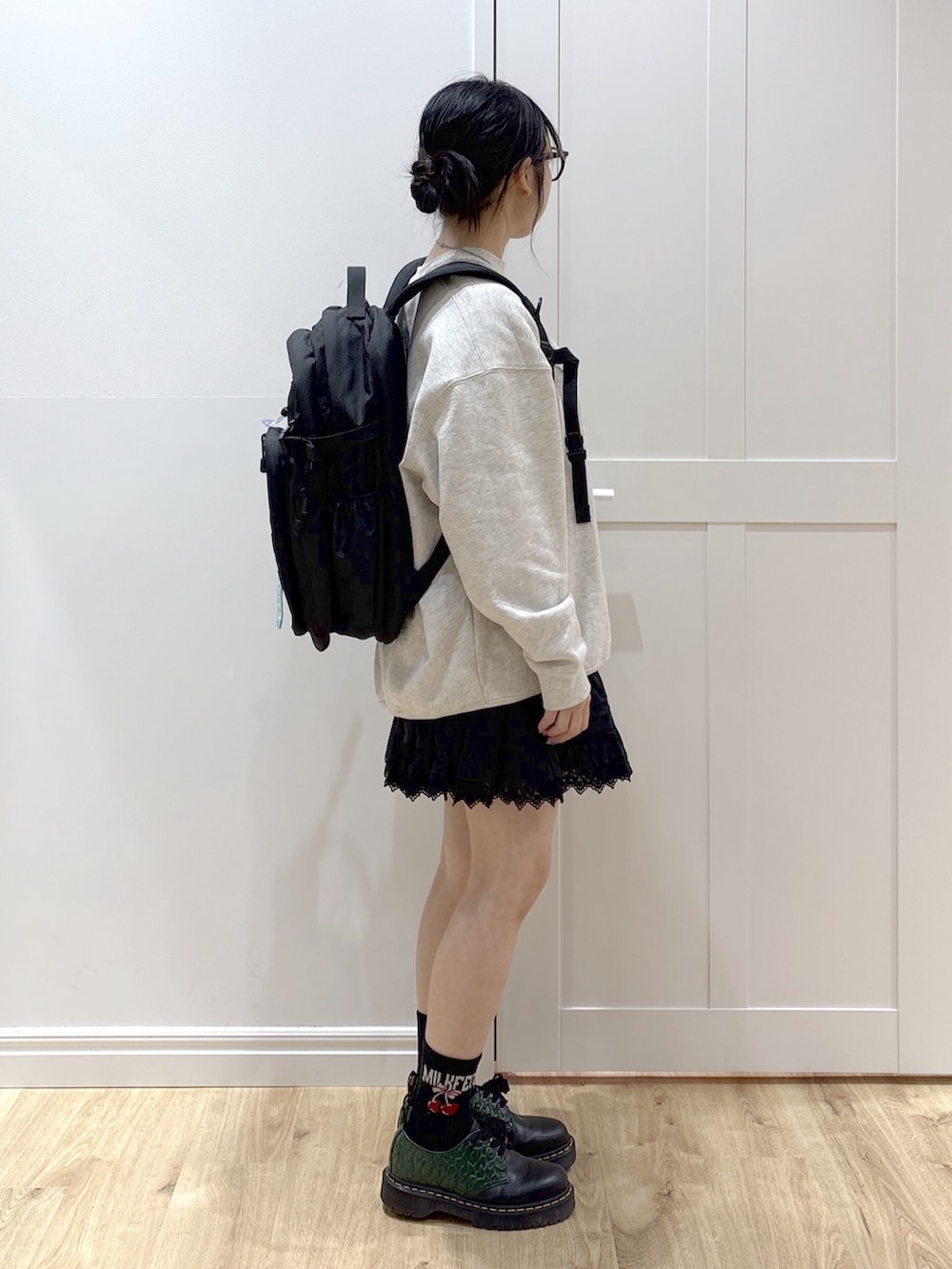 ブラック系のスカート、ベージュ系のスウェット、グリーン系のバックパック/リュックを着用したレディースの春コーディネートの4枚目の写真