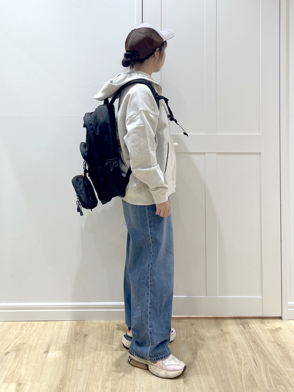 ベージュ系のパーカー、ブルー系のデニムパンツ、ブラック系のカーディガン/ボレロを着用したレディースの冬コーディネートの4枚目の写真