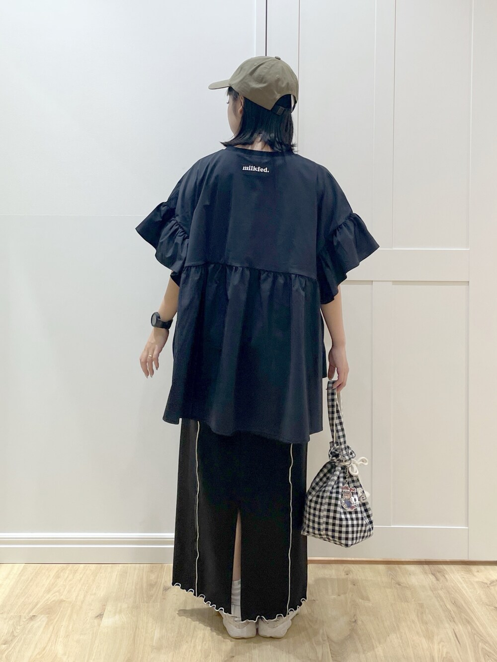 ブラック系のスカート、ブラック系のトートバッグ、ブラック系のラッシュガードを着用したレディースの春コーディネートの2枚目の写真