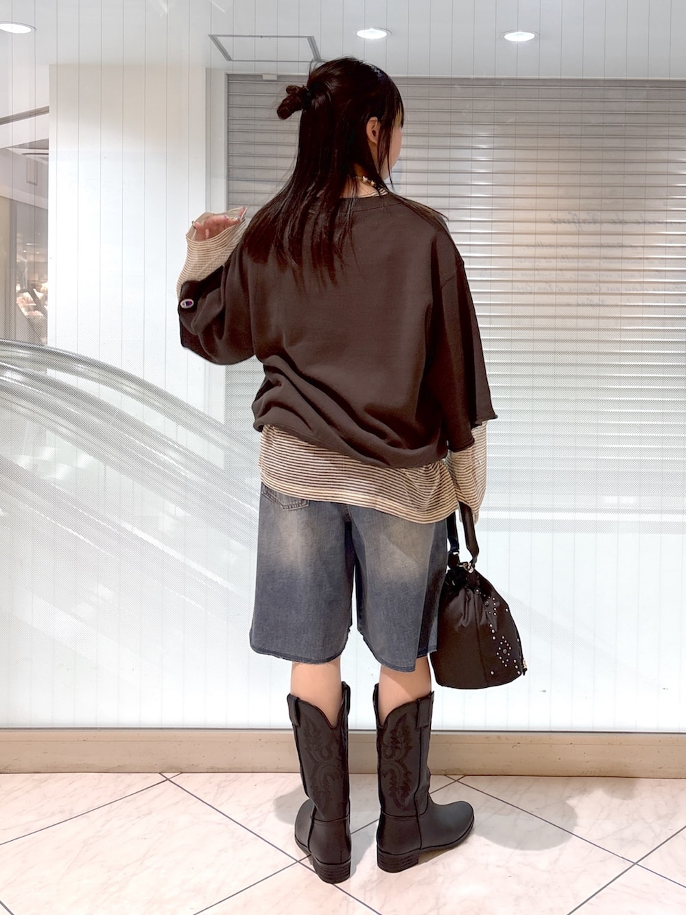 ブラック系のブーツ、ブラック系のショルダーバッグ、ブルー系のその他パンツを着用したレディースの春コーディネートの2枚目の写真