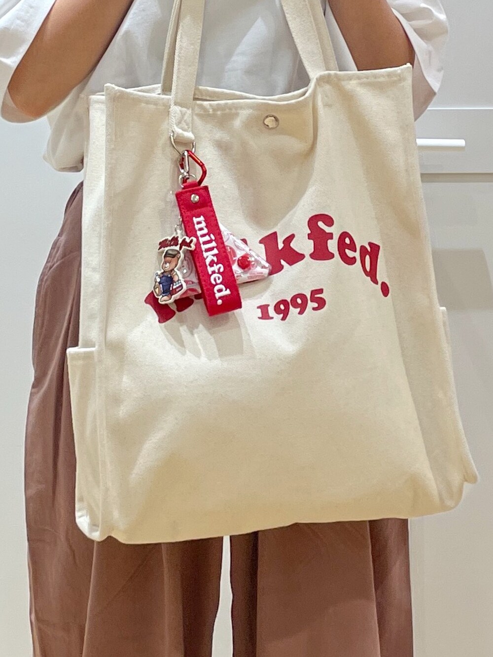 ホワイト系のTシャツ/カットソー、ホワイト系のスニーカー、ホワイト系のトートバッグを着用したレディースの夏コーディネートの5枚目の写真