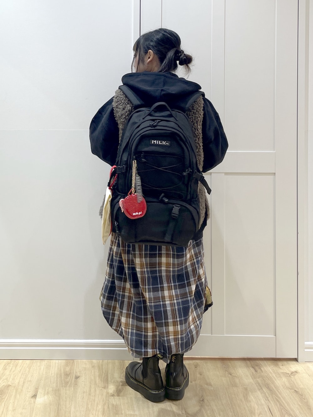 ブラウン系のベスト、イエロー系のワンピース、ブラック系のブーツを着用したレディースの冬コーディネートの4枚目の写真