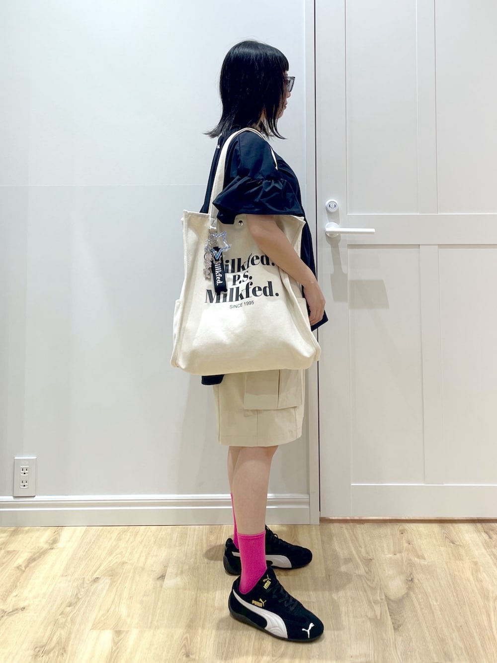 ブラック系のスニーカー、ホワイト系のトートバッグ、ブルー系のサングラスを着用したレディースの夏コーディネートの2枚目の写真