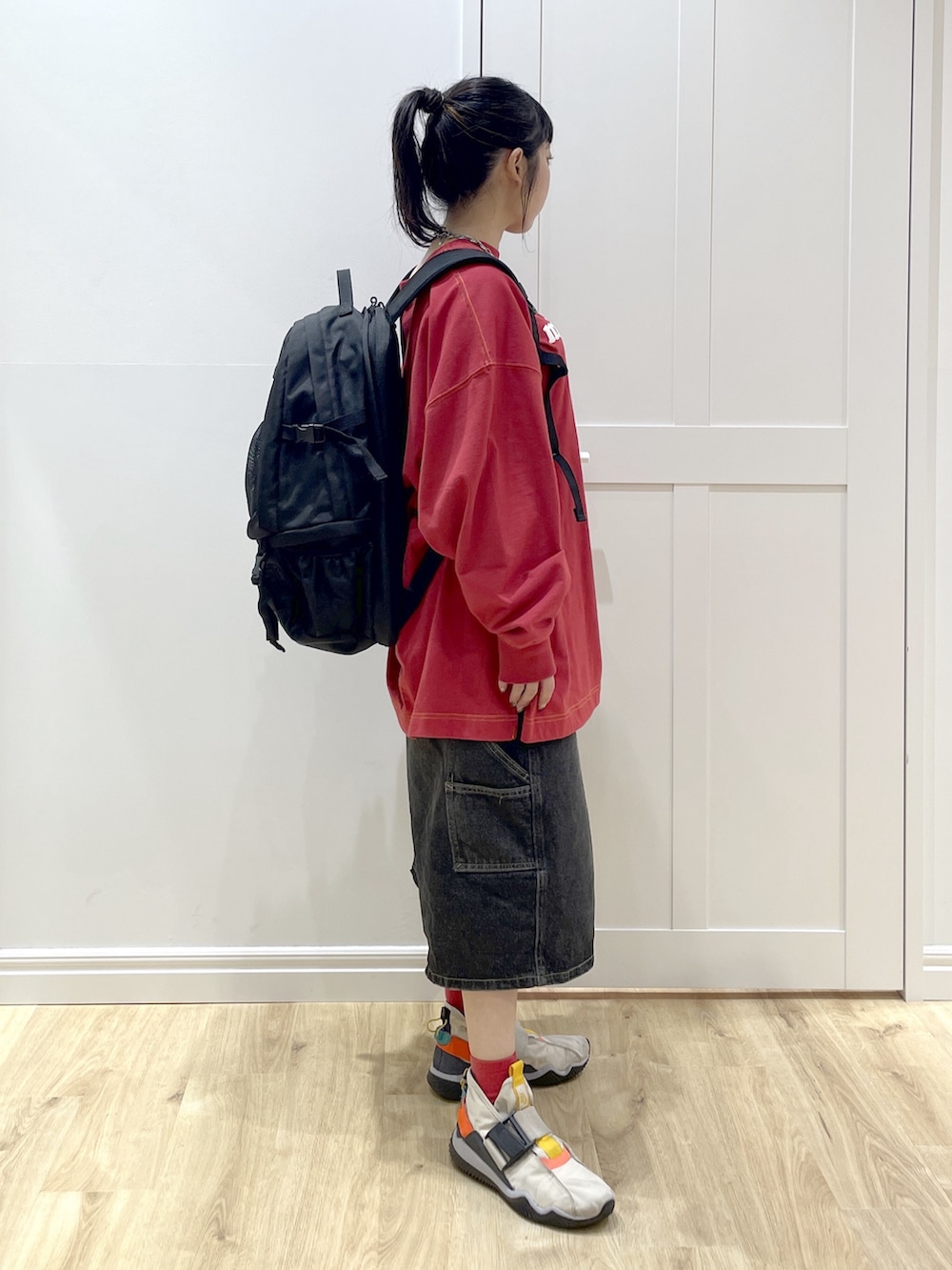 レッド系のバックパック/リュック、ブラック系のデニムパンツ、レッド系のTシャツ/カットソーを着用したレディースの秋コーディネートの4枚目の写真