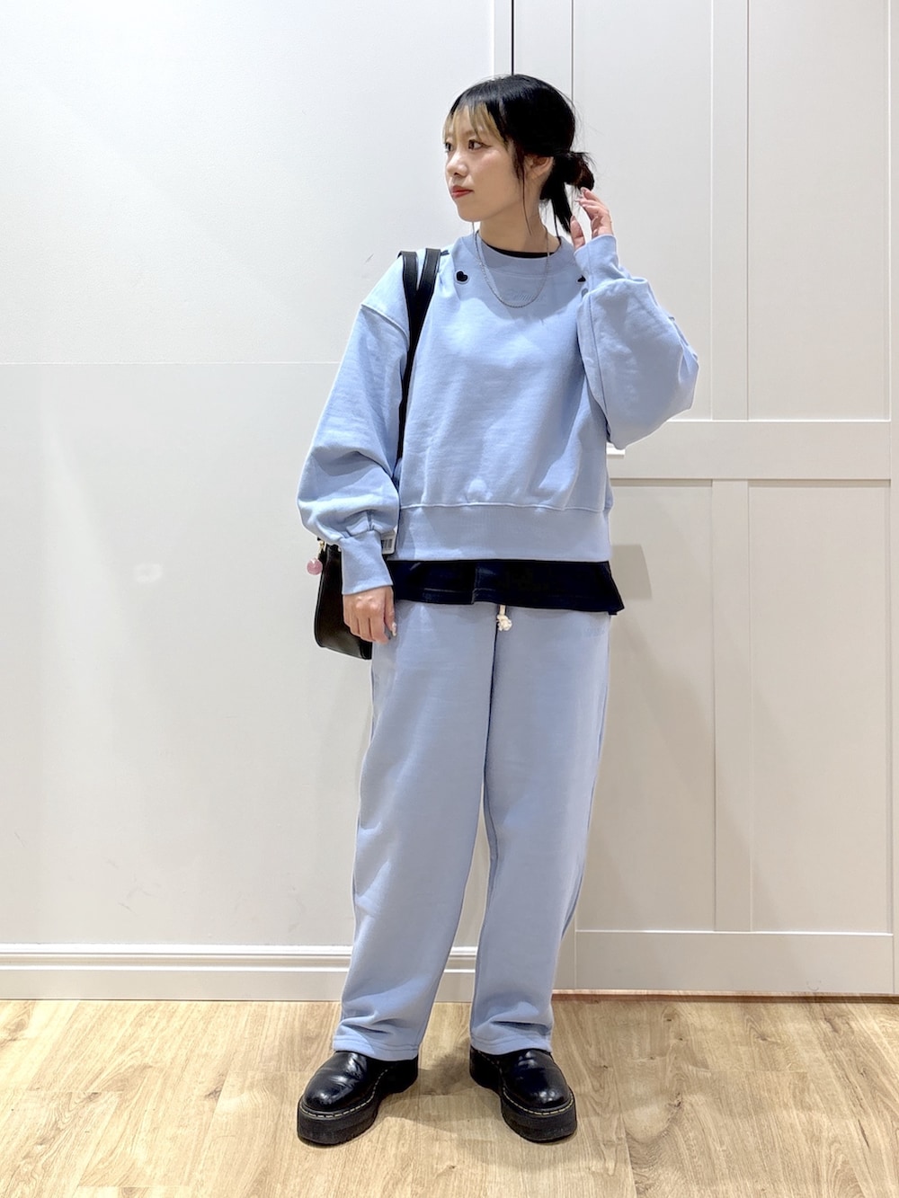ブラック系のブーツ、ブルー系のスウェットパンツ、グリーン系のボストンバッグを着用したレディースの春コーディネートの2枚目の写真