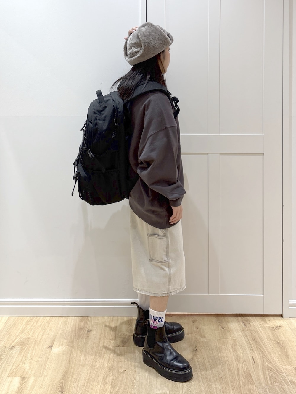 ホワイト系のデニムパンツ、グレー系のスウェット、ブラック系のバックパック/リュックを着用したレディースの冬コーディネートの2枚目の写真