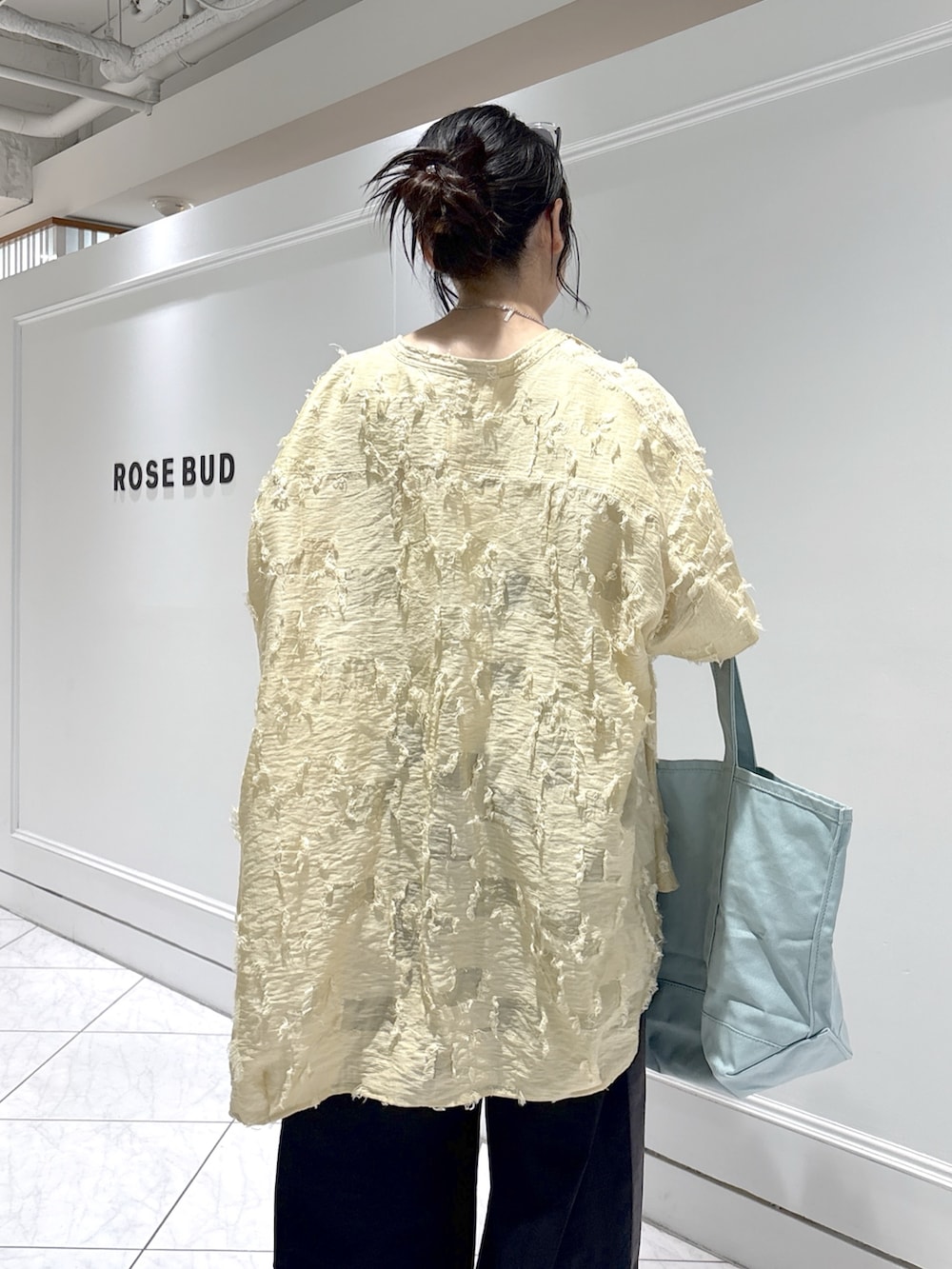 ブルー系のトートバッグ、ベージュ系のシャツ/ブラウス、ホワイト系のベストを着用したレディースの春コーディネートの6枚目の写真