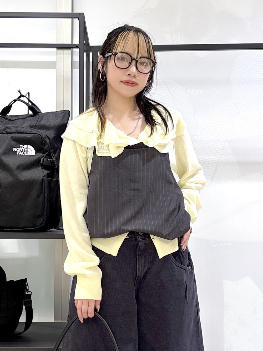 シルバー系のスニーカー、ブラック系のハンドバッグ、ブラック系のデニムパンツを着用したレディースの春コーディネートの5枚目の写真