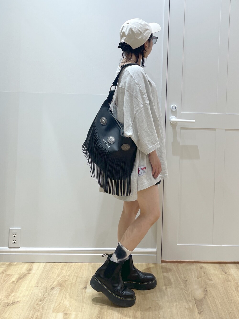 ブラック系のブーツ、ブラック系のショルダーバッグ、ベージュ系のTシャツ/カットソーを着用したレディースの春コーディネートの2枚目の写真