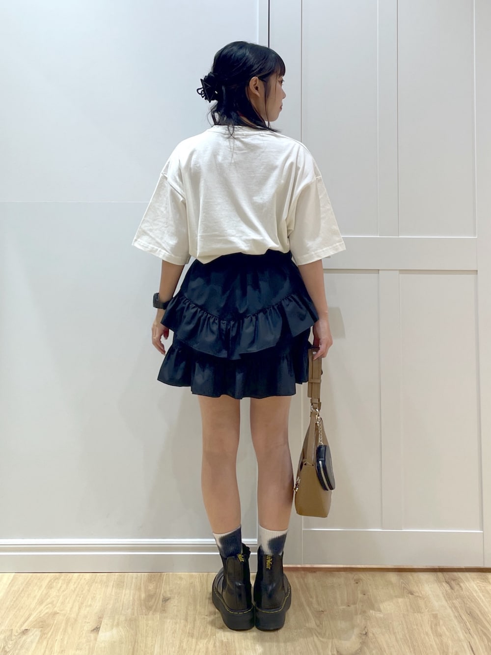 ブラック系のスカート、ホワイト系のTシャツ/カットソー、ブラック系のブーツを着用したレディースの夏コーディネートの2枚目の写真