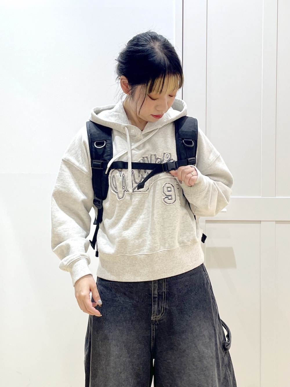 ブラック系のデニムパンツ、ベージュ系のパーカー、レッド系のバックパック/リュックを着用したレディースの冬コーディネートの8枚目の写真