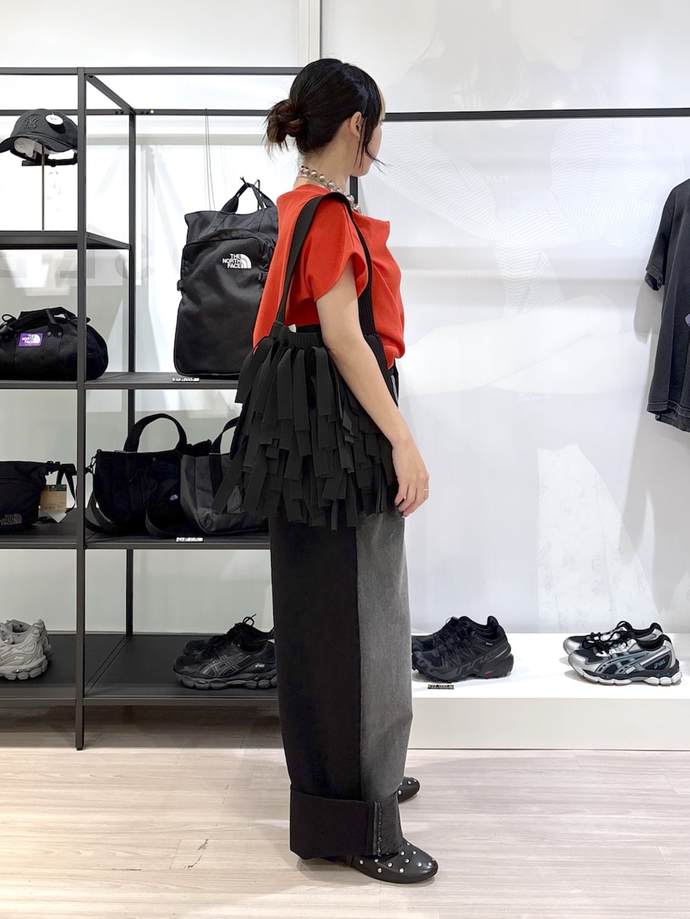ブラック系のショルダーバッグ、ブラック系のその他シューズ、レッド系のTシャツ/カットソーを着用したレディースの春コーディネートの3枚目の写真