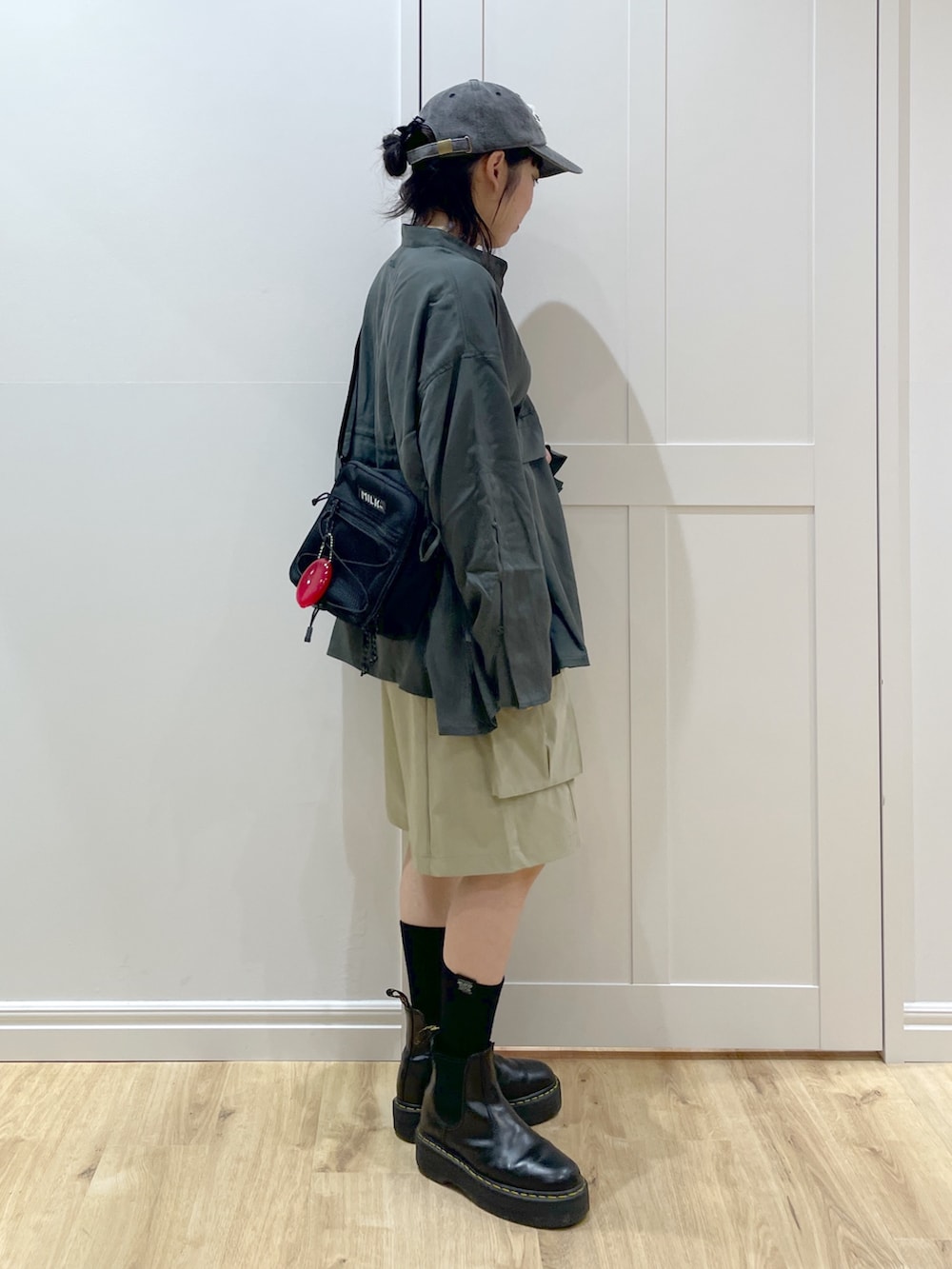 ブラック系のブーツ、グリーン系のシャツ/ブラウス、レッド系のショルダーバッグを着用したレディースの夏コーディネートの3枚目の写真