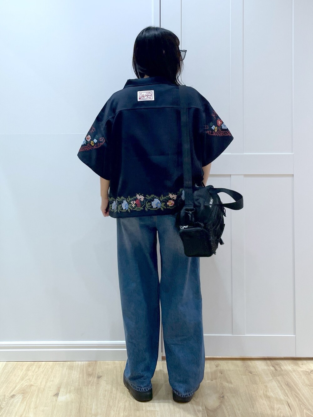 ブルー系のデニムパンツ、ブラック系のブーツ、レッド系のショルダーバッグを着用したレディースの夏コーディネートの3枚目の写真