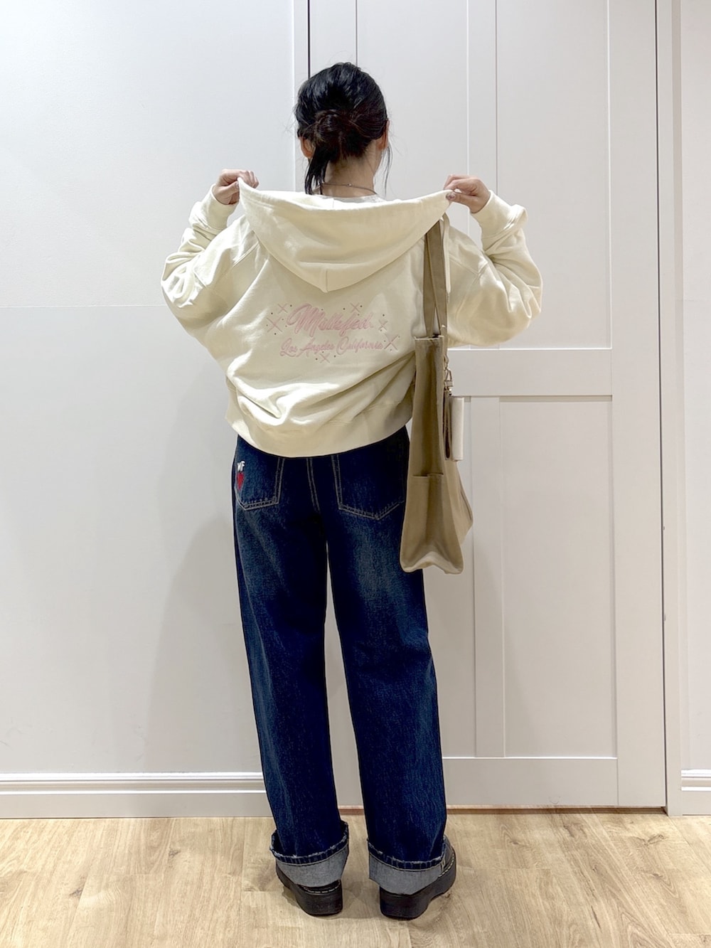 ブラック系のブーツ、ブルー系のデニムパンツ、ホワイト系のパーカーを着用したレディースの春コーディネートの2枚目の写真