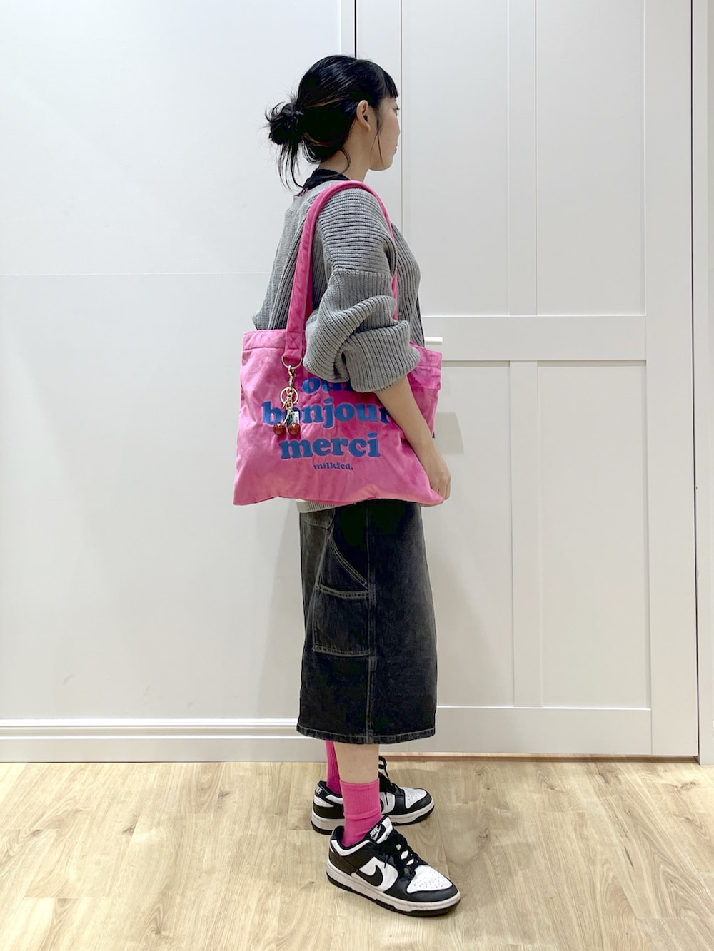 ホワイト系のスニーカー、ブラック系のデニムパンツ、グレー系のカーディガン/ボレロを着用したレディースの秋コーディネートの2枚目の写真