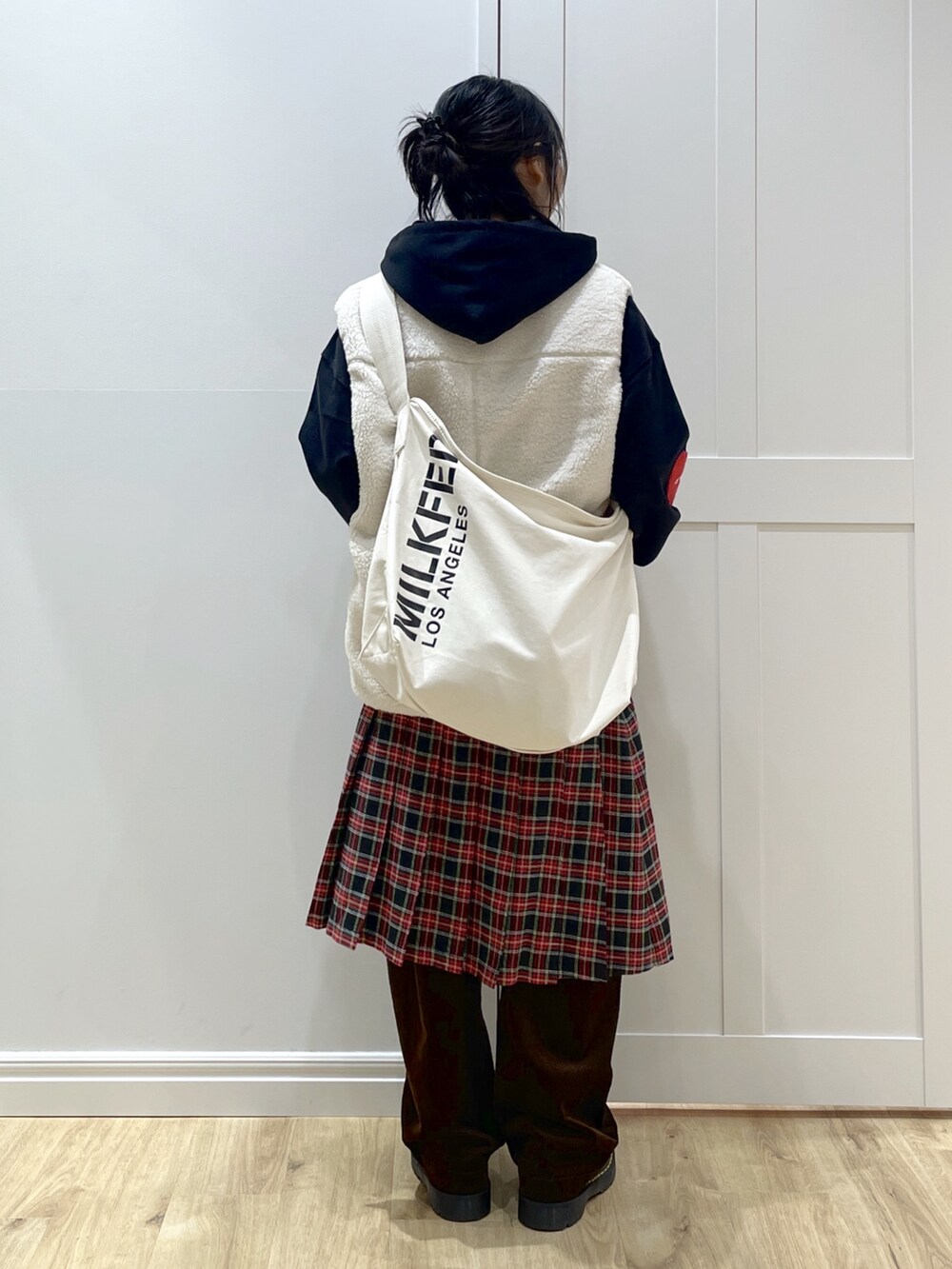 ホワイト系のベスト、ブラック系のパーカー、ブラック系のスカートを着用したレディースの秋コーディネートの2枚目の写真