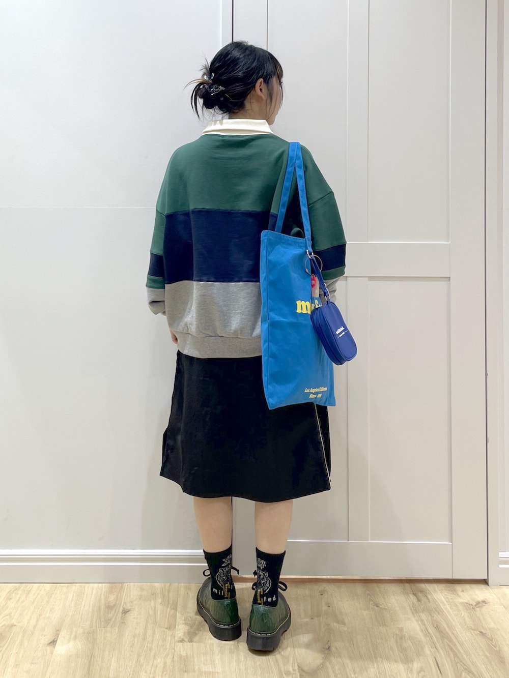 グリーン系のスウェット、ブラック系のスカート、ブルー系のトートバッグを着用したレディースの冬コーディネートの6枚目の写真