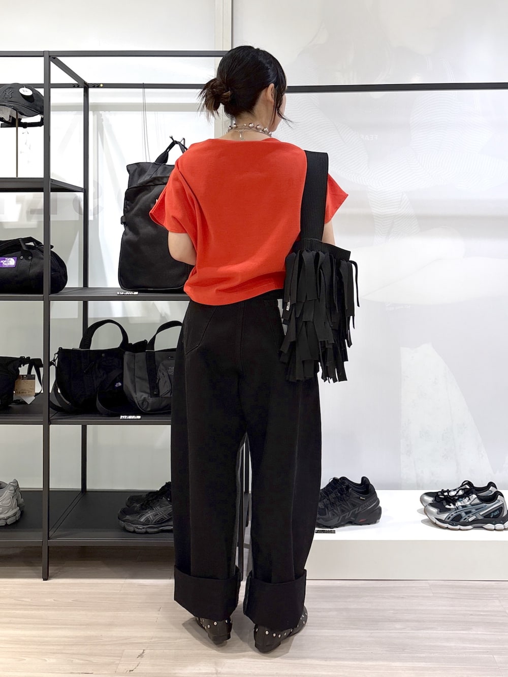 ブラック系のショルダーバッグ、ブラック系のその他シューズ、レッド系のTシャツ/カットソーを着用したレディースの春コーディネートの2枚目の写真