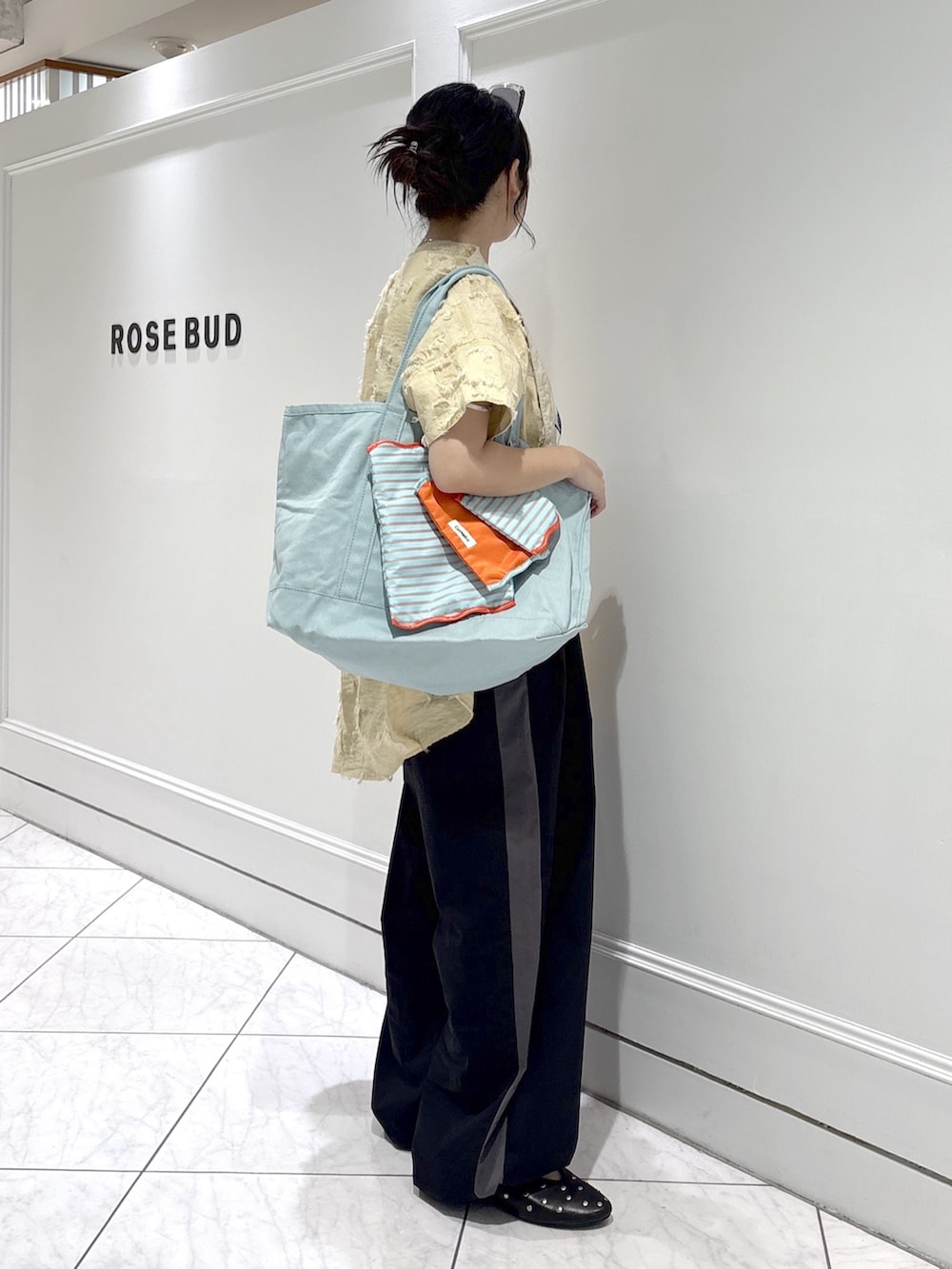 ブルー系のトートバッグ、ベージュ系のシャツ/ブラウス、ホワイト系のベストを着用したレディースの春コーディネートの2枚目の写真