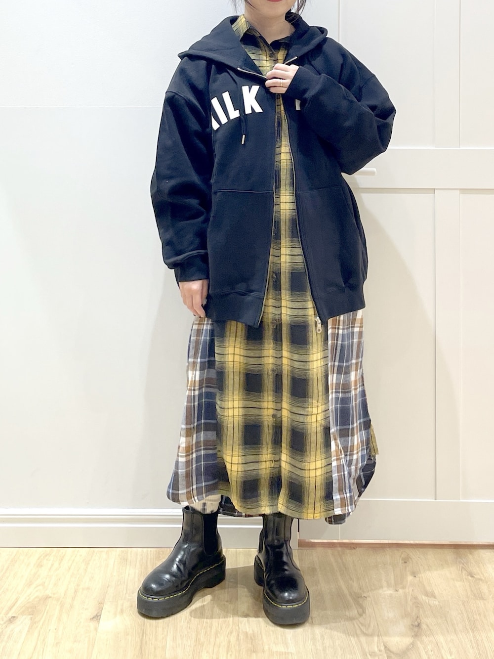 ブラウン系のベスト、イエロー系のワンピース、ブラック系のブーツを着用したレディースの冬コーディネートの5枚目の写真