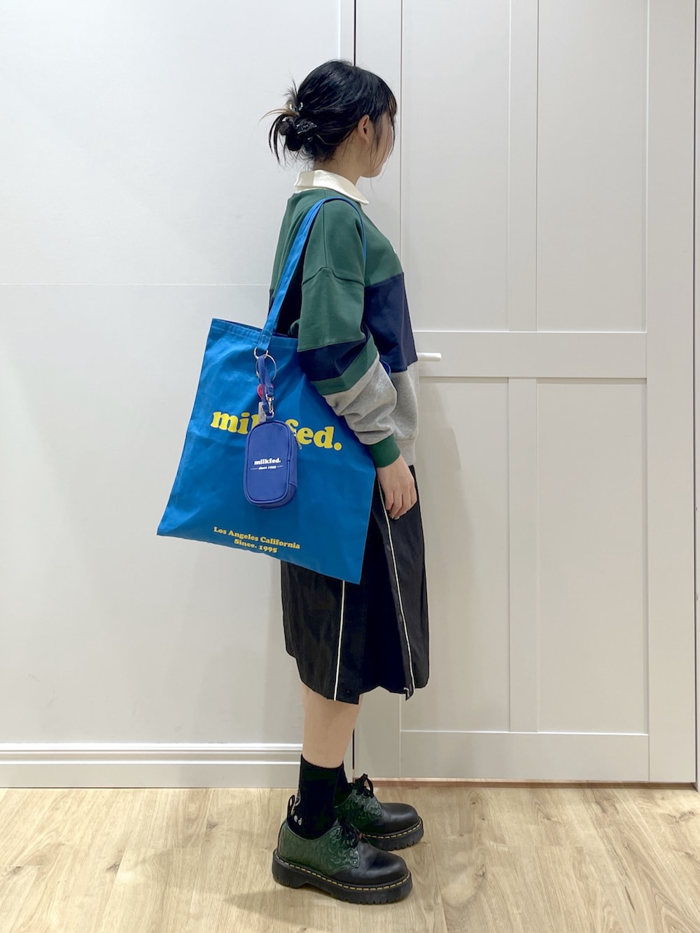 グリーン系のスウェット、ブラック系のスカート、ブルー系のトートバッグを着用したレディースの冬コーディネートの5枚目の写真