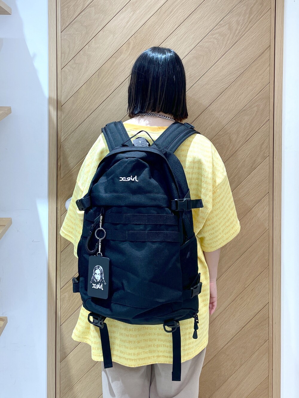 ブラック系のバックパック/リュック、イエロー系のTシャツ/カットソー、ベージュ系のスウェットパンツを着用したレディースの春コーディネートの3枚目の写真