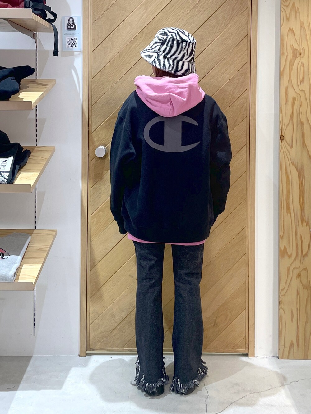 ブラック系のデニムパンツ、ブラック系のブーツ、ピンク系のパーカーを着用したレディースの秋コーディネートの2枚目の写真