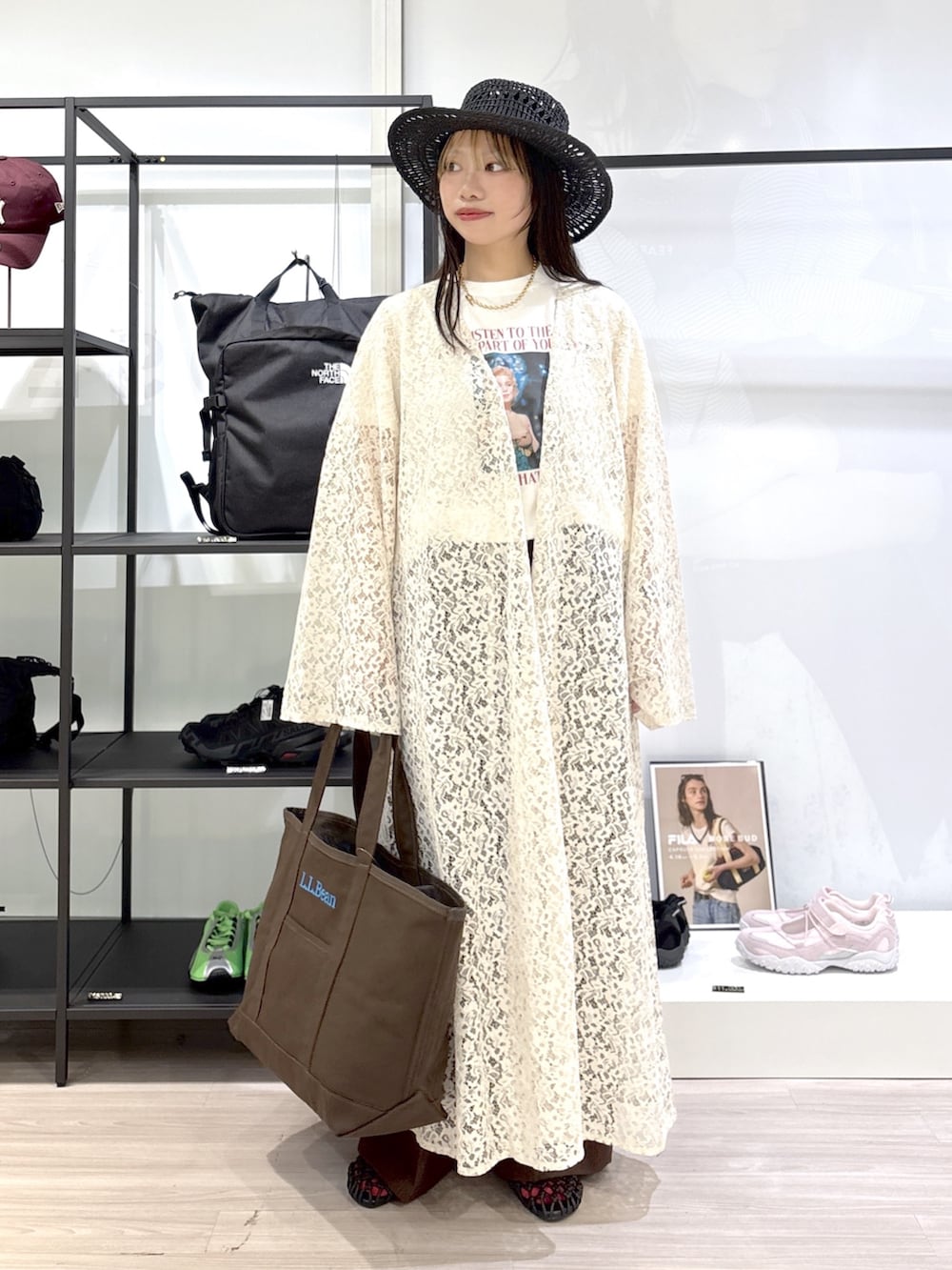ブラウン系のトートバッグ、ブラウン系のサンダル、ホワイト系のTシャツ/カットソーを着用したレディースの春コーディネートの4枚目の写真