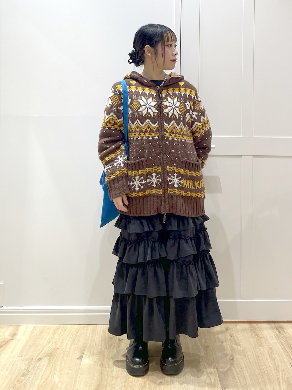 ブラウン系のその他アウター、ブラック系のスカート、ブラック系のブーツを着用したレディースの冬コーディネートの5枚目の写真