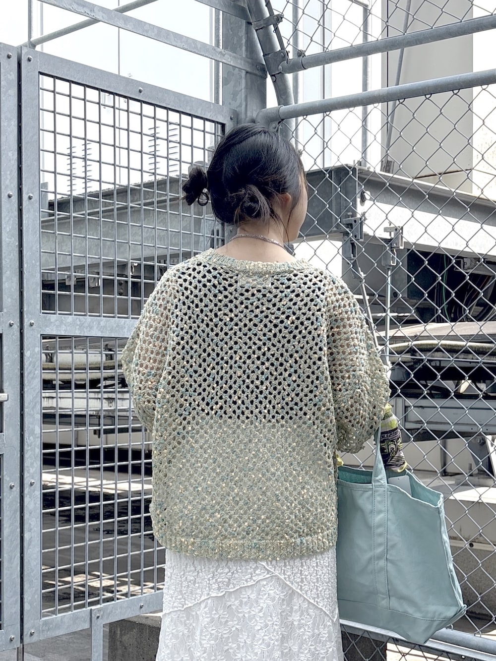 ブラック系のブーツ、ブルー系のニット/セーター、ホワイト系のスカートを着用したレディースの春コーディネートの6枚目の写真