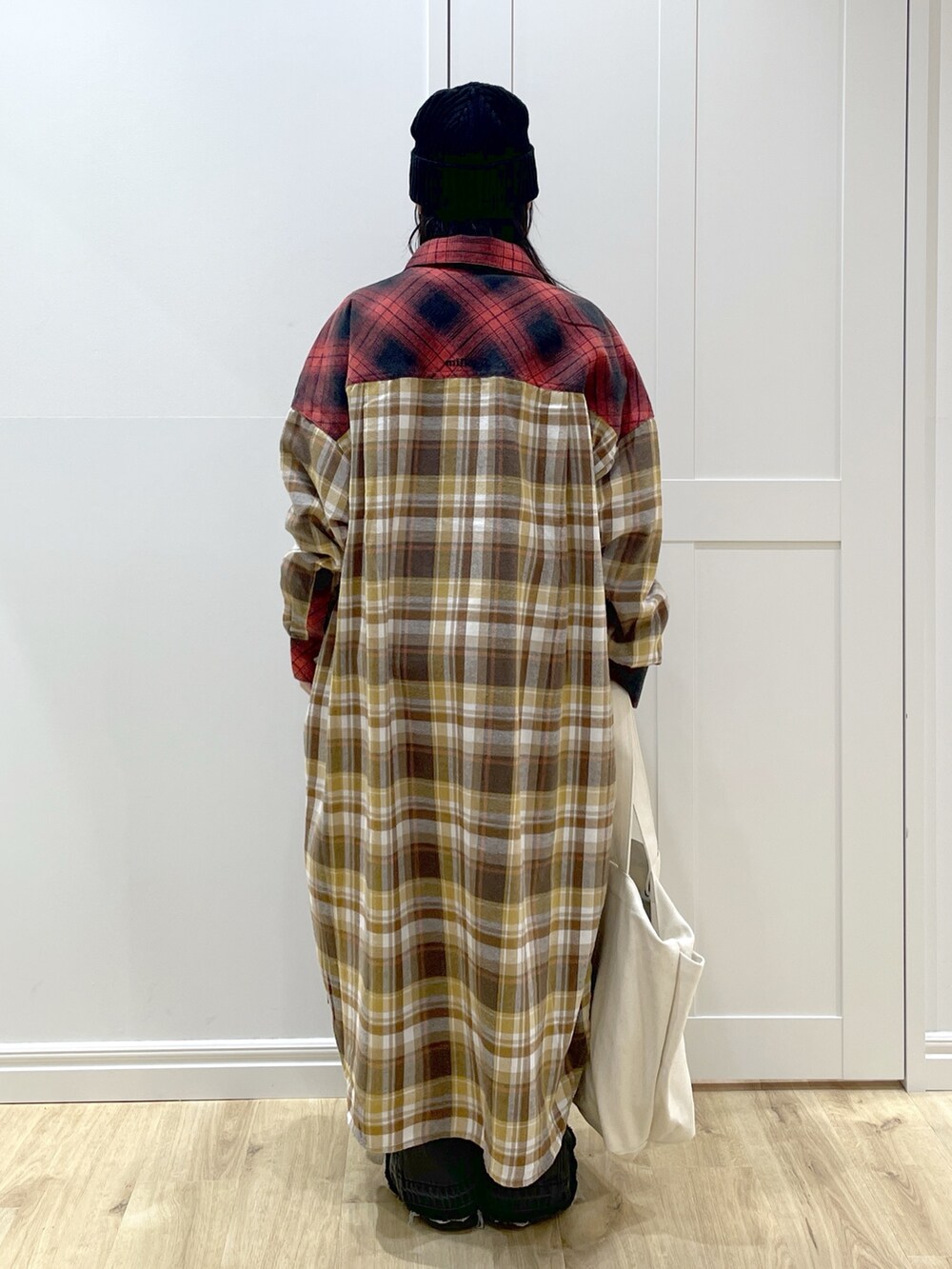 ブラック系のデニムパンツ、レッド系のワンピース、ホワイト系のスウェットを着用したレディースの秋コーディネートの4枚目の写真