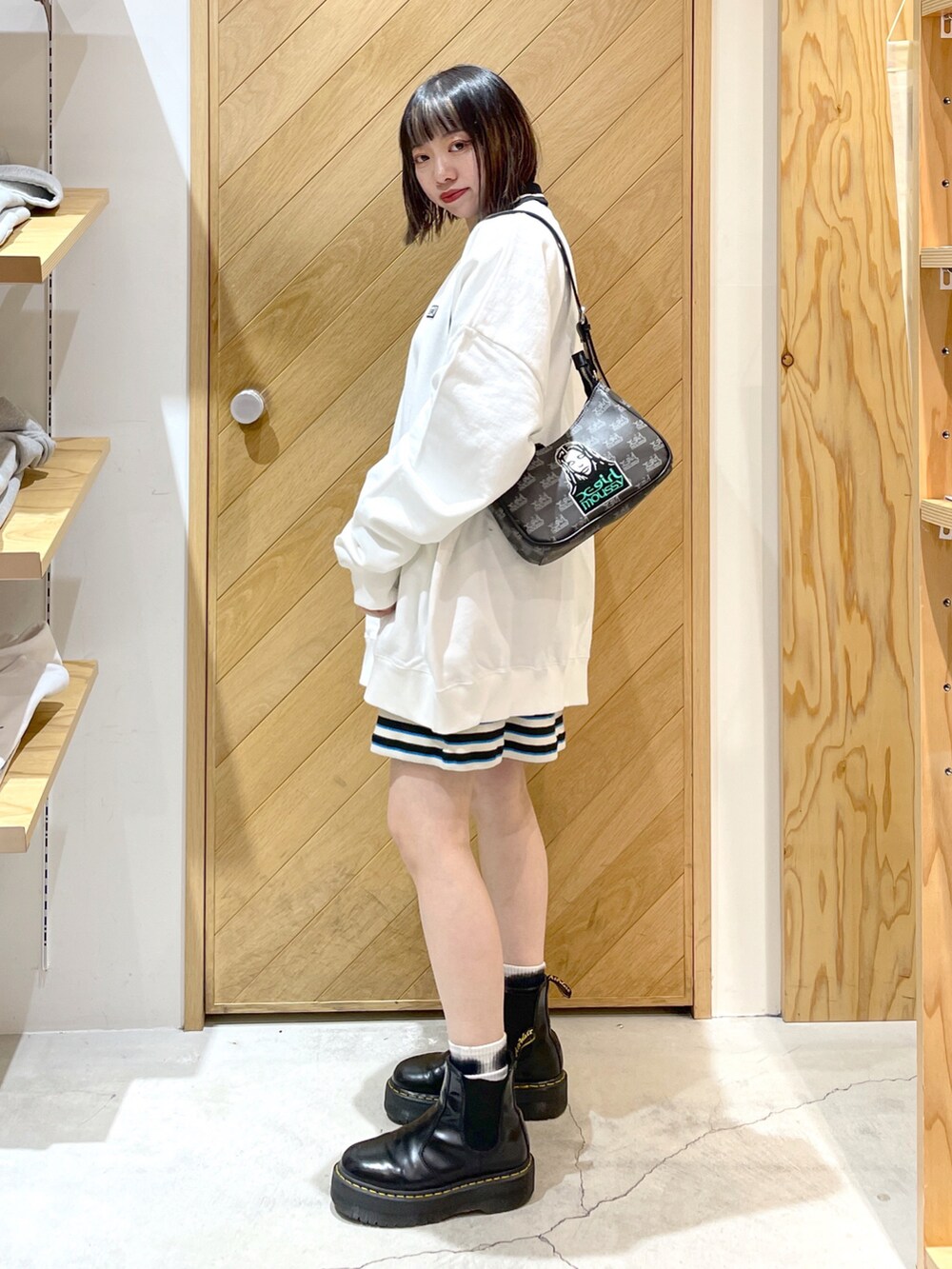 ホワイト系のスウェット、ブラック系のワンピース、ブラック系のブーツを着用したレディースの春コーディネートの2枚目の写真