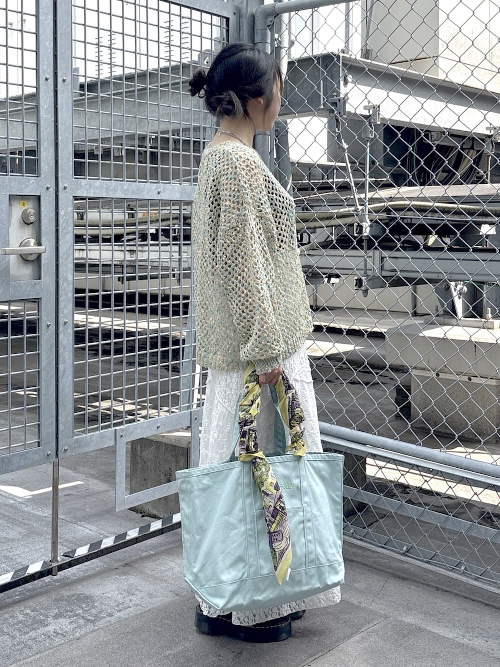 ブラック系のブーツ、ブルー系のニット/セーター、ホワイト系のスカートを着用したレディースの春コーディネートの2枚目の写真