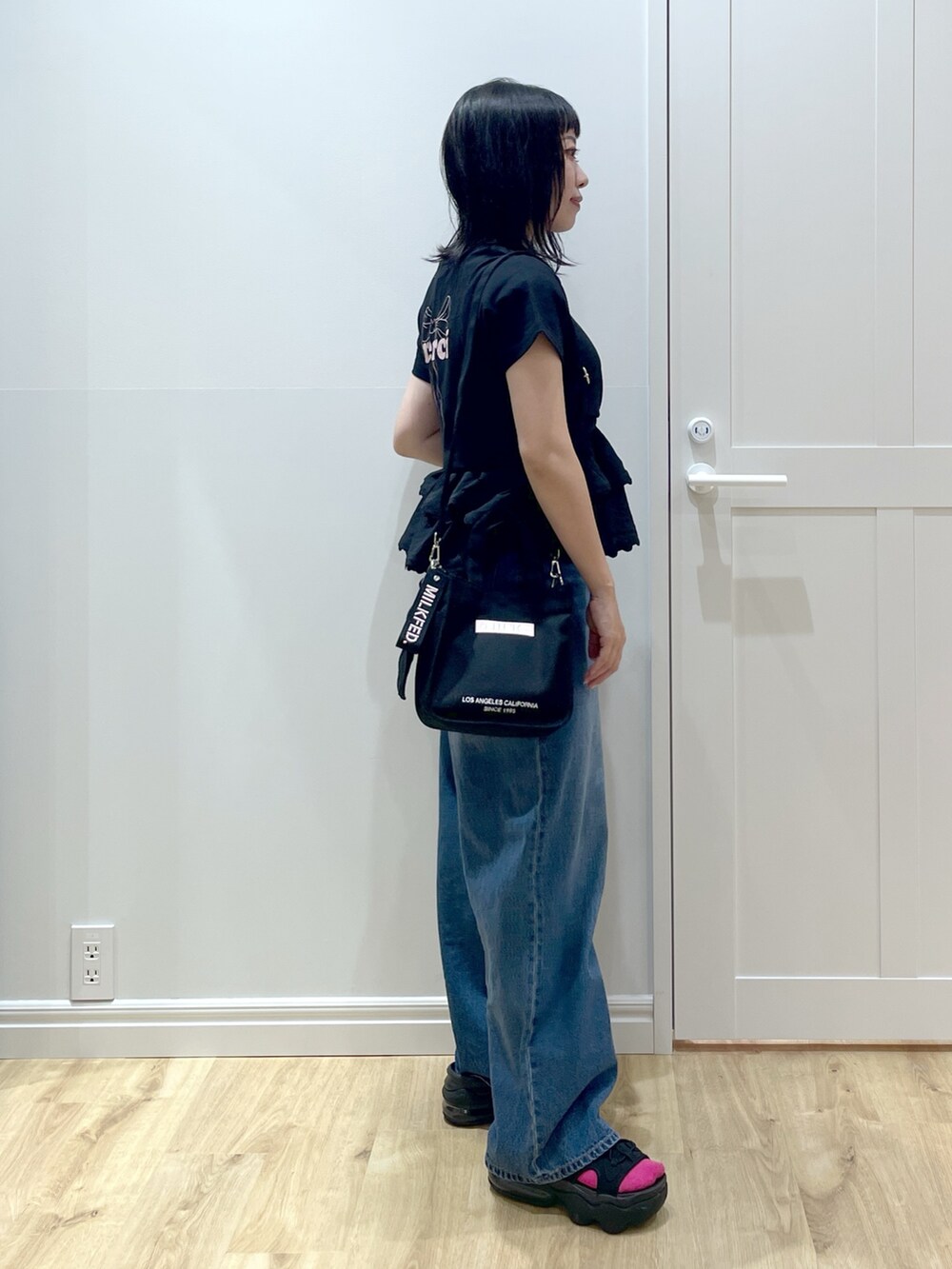 ピンク系のショルダーバッグ、ブルー系のデニムパンツ、ブラック系のサンダルを着用したレディースの夏コーディネートの3枚目の写真