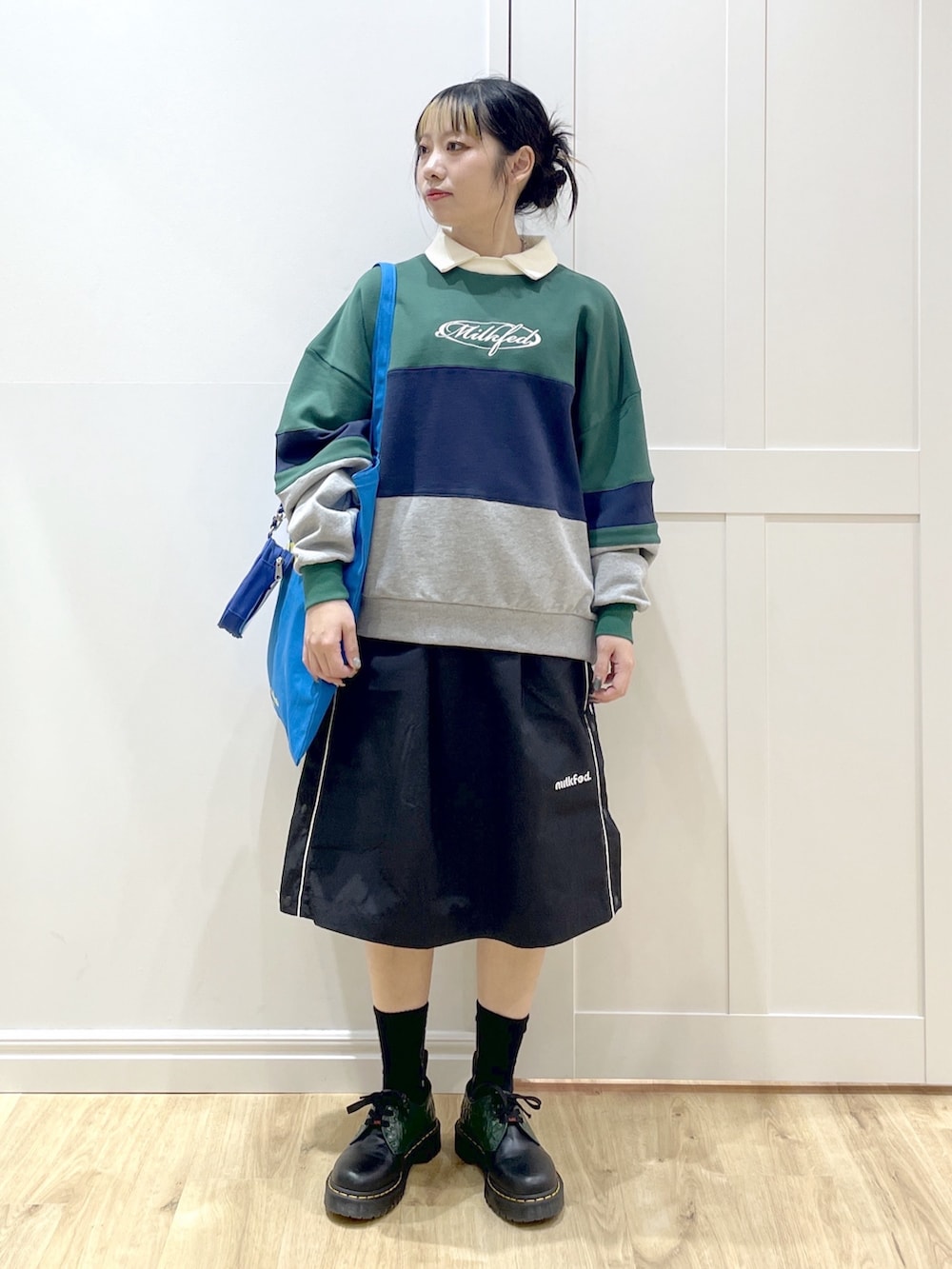 グリーン系のスウェット、ブラック系のスカート、ブルー系のトートバッグを着用したレディースの冬コーディネートの2枚目の写真