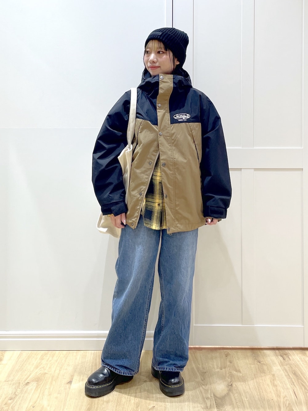 ブルー系のデニムパンツ、イエロー系のシャツ/ブラウス、ベージュ系のマウンテンパーカーを着用したレディースの冬コーディネートの2枚目の写真