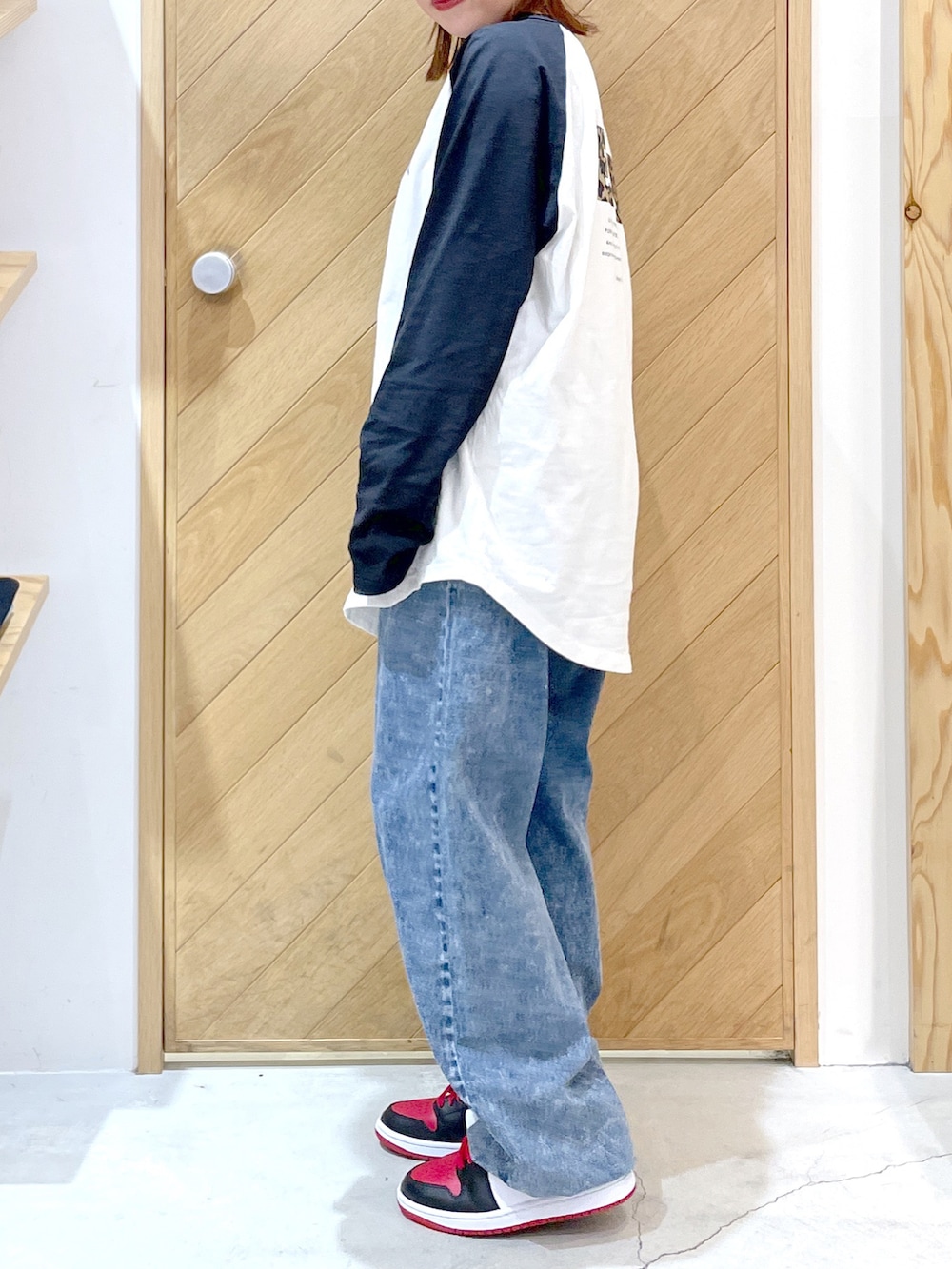 ブルー系のデニムパンツ、レッド系のスニーカー、ホワイト系のTシャツ/カットソーを着用したレディースの秋コーディネートの3枚目の写真