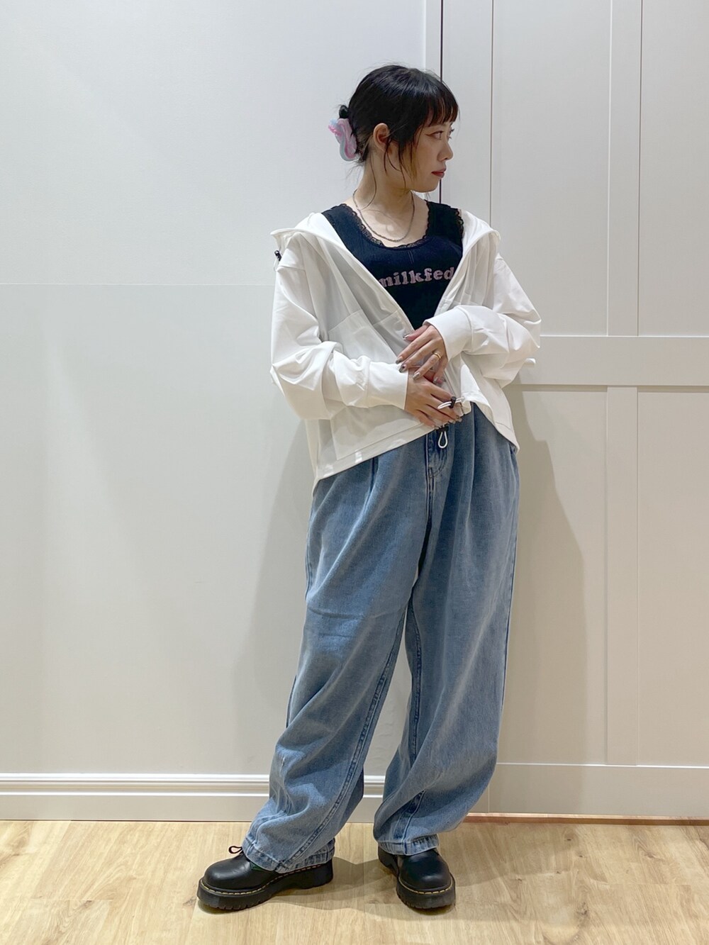 ブラック系のタンクトップ、ブルー系のデニムパンツ、ホワイト系のラッシュガードを着用したレディースの春コーディネートの2枚目の写真