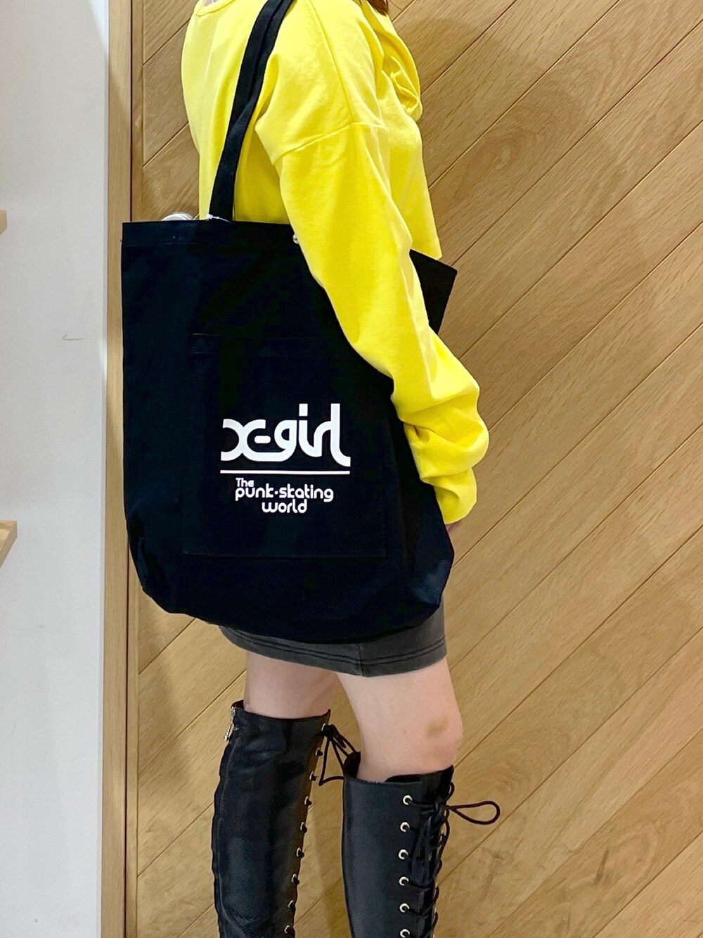 ブラック系のブーツ、イエロー系のTシャツ/カットソー、ブラック系のスカートを着用したレディースの秋コーディネートの3枚目の写真