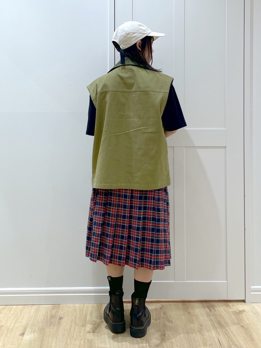 ブラック系のブーツ、ブルー系のスカート、グリーン系のベストを着用したレディースの秋コーディネートの3枚目の写真