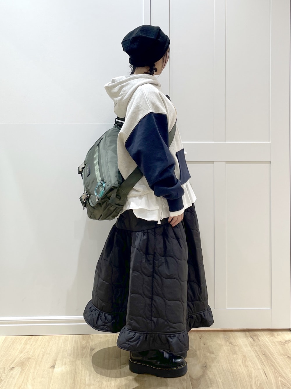 ブラック系のブーツ、グリーン系のメッセンジャーバッグ、ブラック系のスカートを着用したレディースの冬コーディネートの2枚目の写真