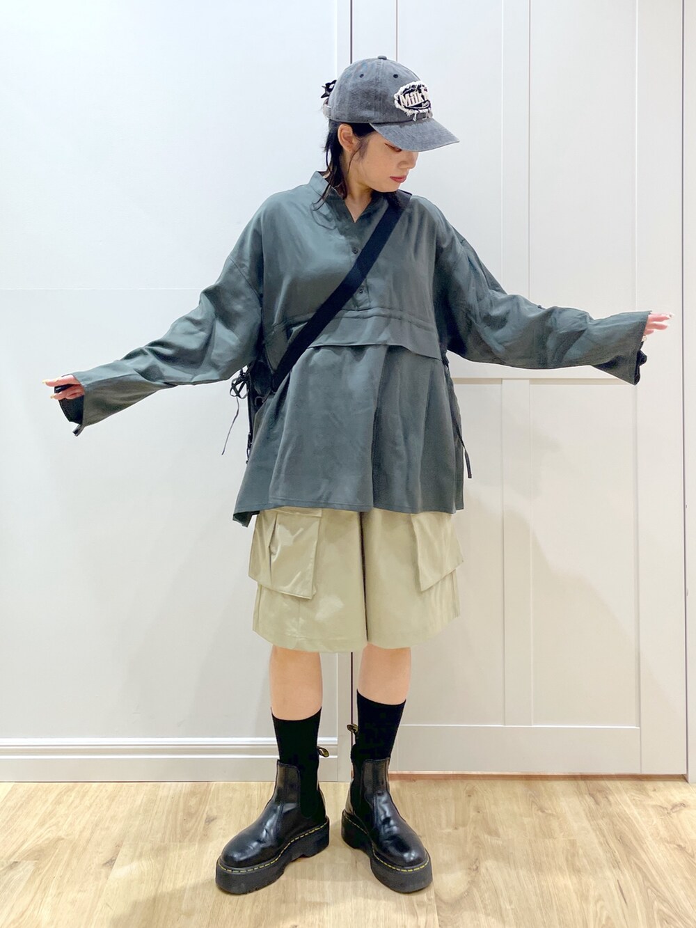 ブラック系のブーツ、グリーン系のシャツ/ブラウス、レッド系のショルダーバッグを着用したレディースの夏コーディネートの2枚目の写真