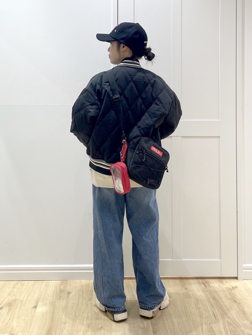 ブルー系のデニムパンツ、ベージュ系のスウェット、レッド系のショルダーバッグを着用したレディースの冬コーディネートの5枚目の写真