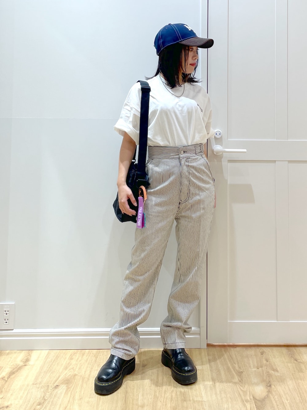 パープル系のショルダーバッグ、ブラック系のブーツ、ブラック系のその他パンツを着用したレディースの夏コーディネートの2枚目の写真